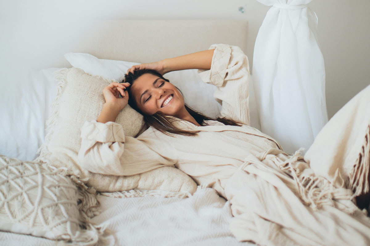 young woman relaxing and smiling on a bed