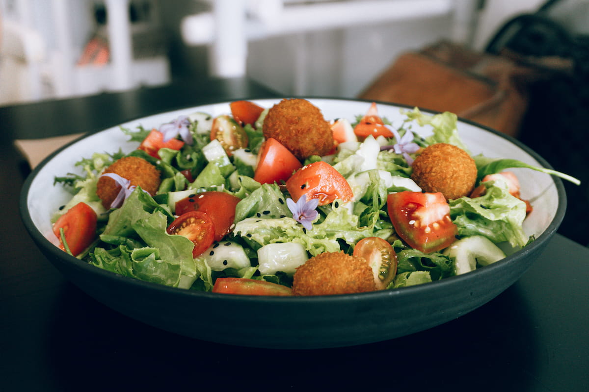 Fresh green salad with tomatoes, cucumbers, and golden-brown falafel balls.