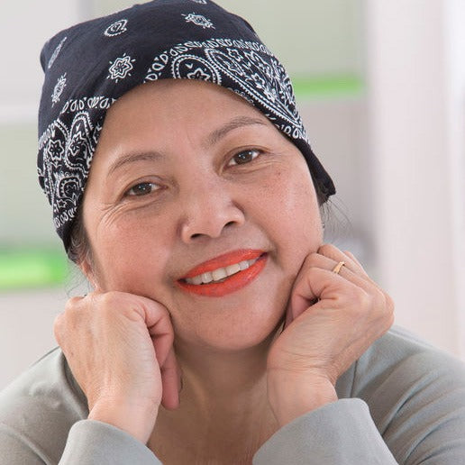 smiling middle-aged woman with bandana over her balding head from chemo