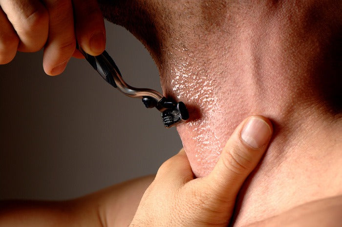 close up on man shaving his neck with a razor