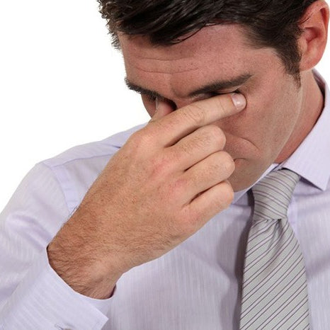 man in tie pressing fingers to his closed eyes in pain