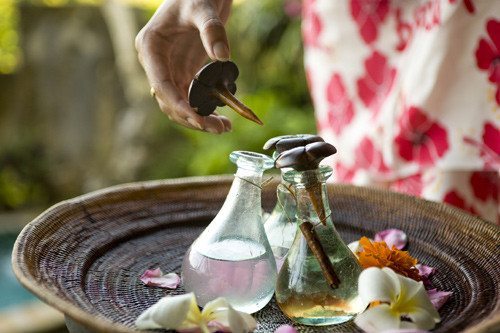 woman's hand holding a bottle stopper over aromatherapy bottles